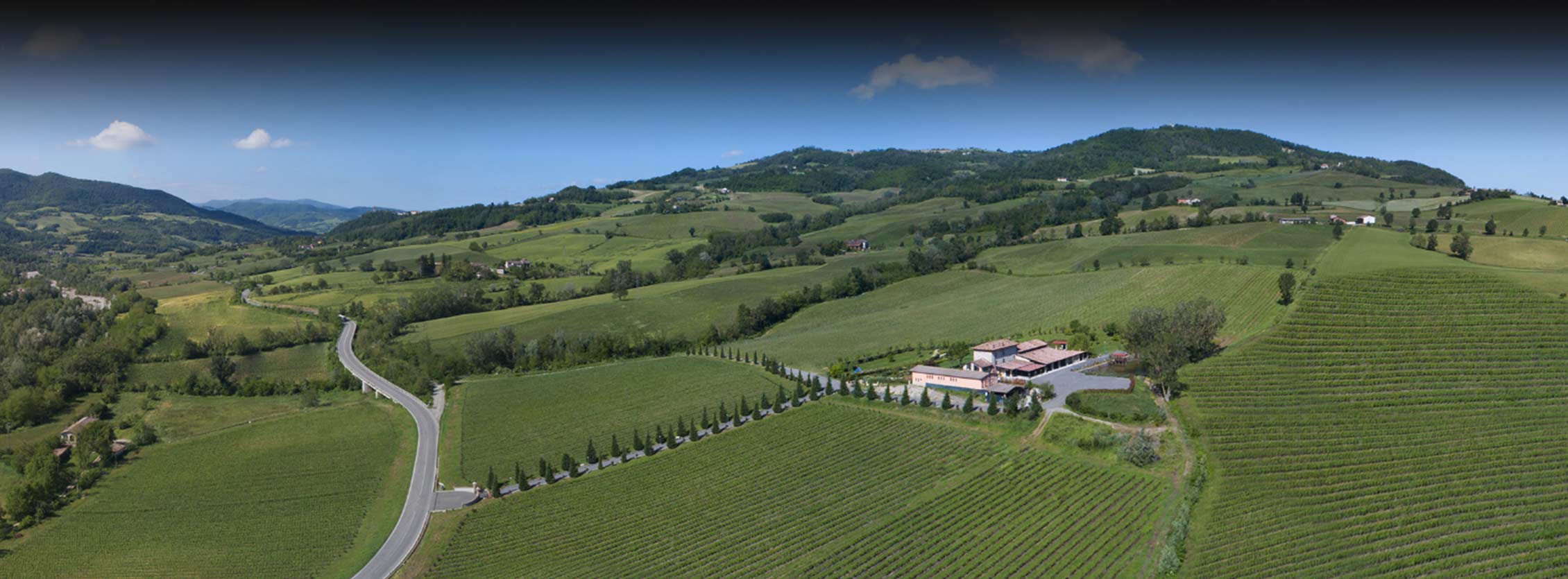 Veduta aerea dl territorio della Alta Val Tidone. In primo piano la tenuta con il suo parco ed i vitigni. Sullo sfondo il paesaggio collinare.